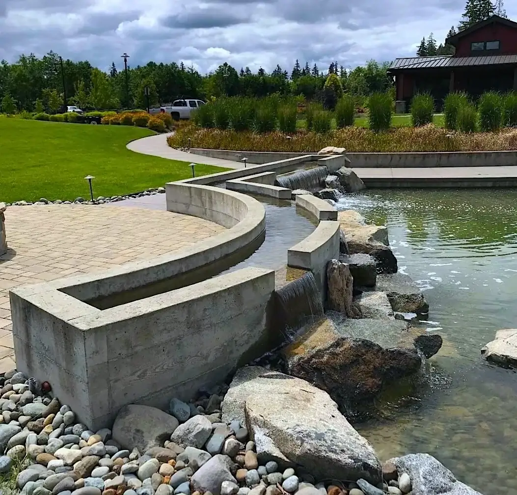Curved architectural concrete retaining wall and water feature in Puyallup, with a patterned concrete patio.