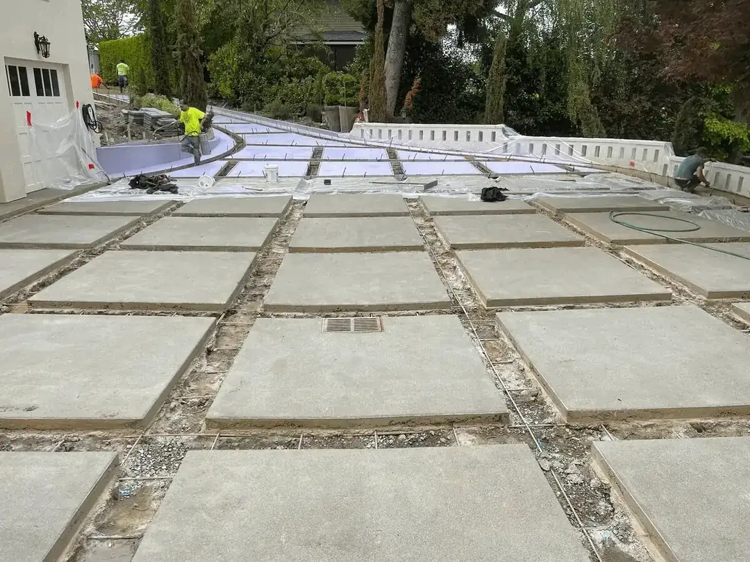Wide view of the driveway construction showing the grid of concrete pads and an integrated channel drain.