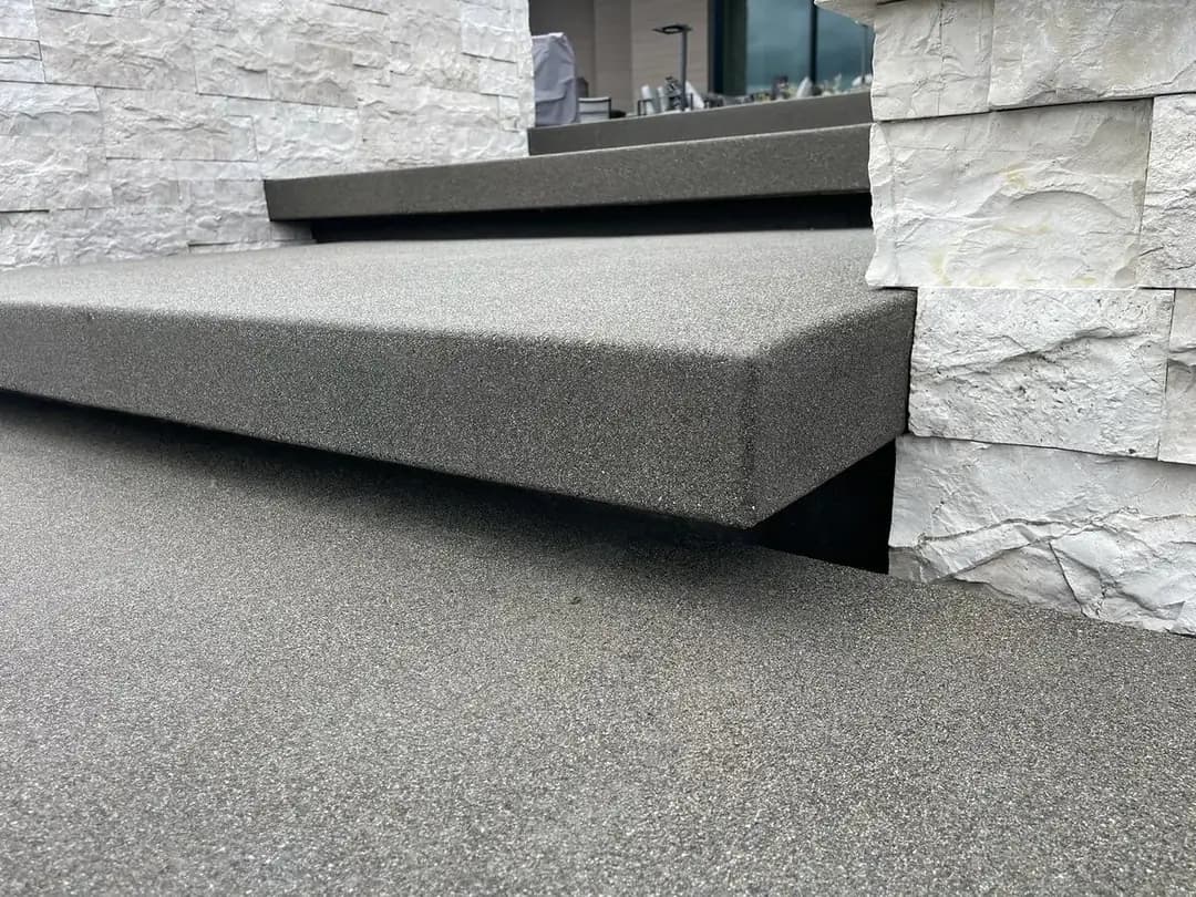 Detail view showing the thick profile and cantilevered design of a floating concrete step against a stone wall.