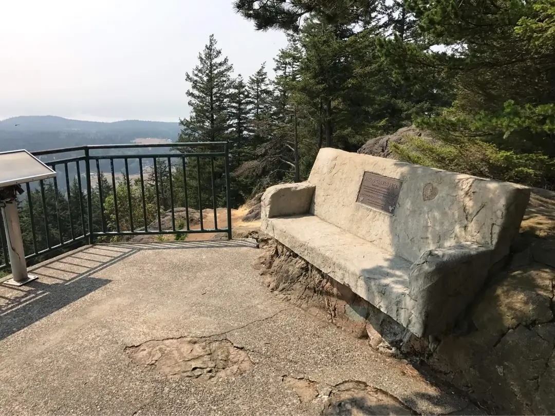 Side view of a custom concrete memorial bench with a natural stone texture at a scenic overlook in Tacoma.