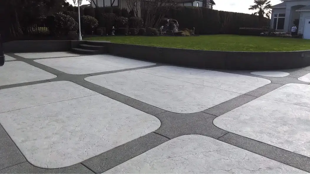 Wide view of a stamped concrete driveway with exposed aggregate borders and a retaining wall in Tacoma, WA.