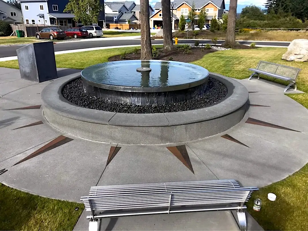 Overhead view of a custom concrete water feature and plaza with an inlaid compass rose design in Bellevue, WA.