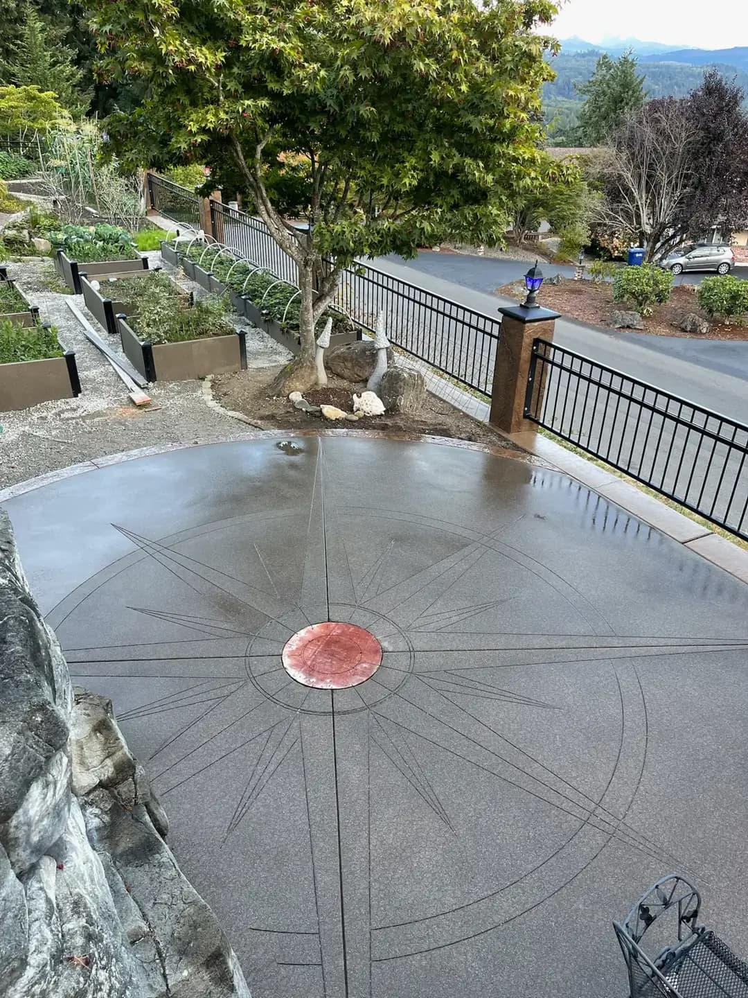 Overhead view of a custom concrete patio with a compass design in Puyallup, WA, next to tiered garden planters.