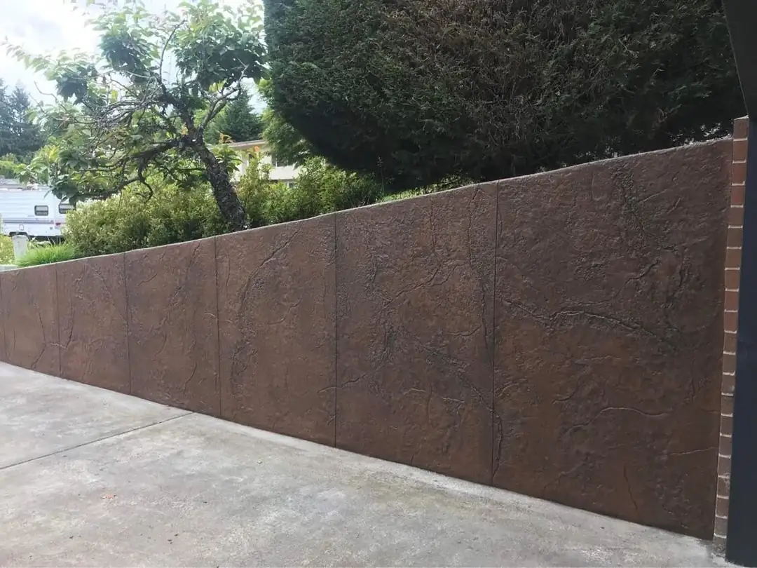 Long view of a brown stamped concrete retaining wall with vertical control joints for stability.