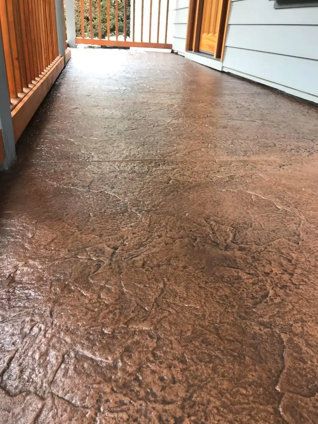 Angled view of a sealed stamped concrete porch floor, highlighting the rich brown color and sheen.