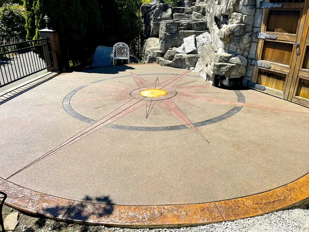 Finished custom concrete patio in Puyallup with a multi-color sand finish compass rose and stamped border.